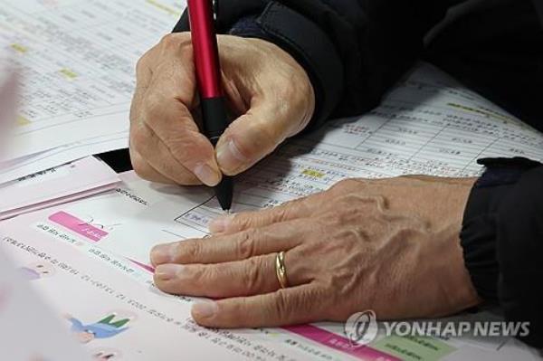 An elderly job seeker fills out an application form at a job fair in Seoul on Dec. 13, 2023. (Yonhap)